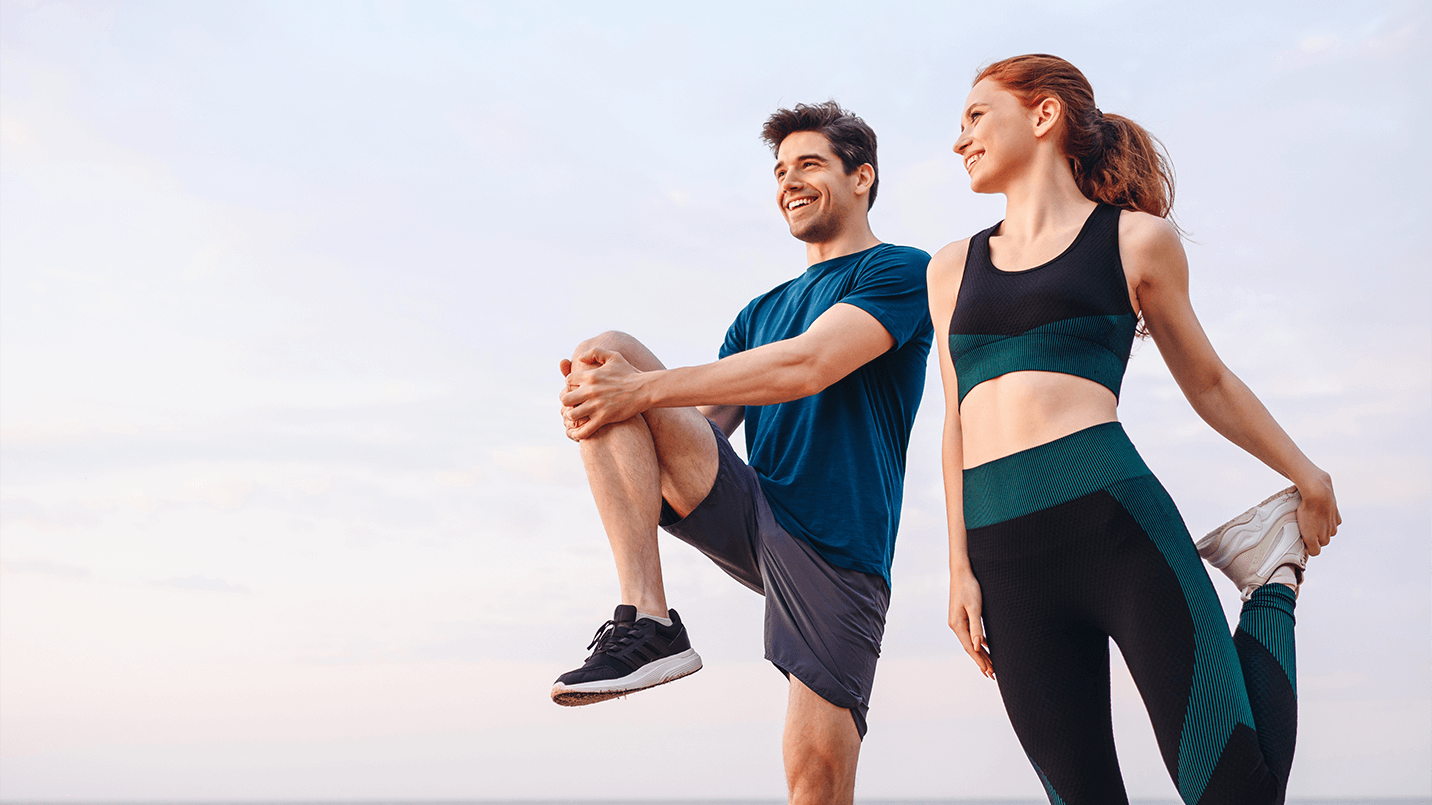 a man and woman wearing athletic clothing and stretching outside in preparation for a run