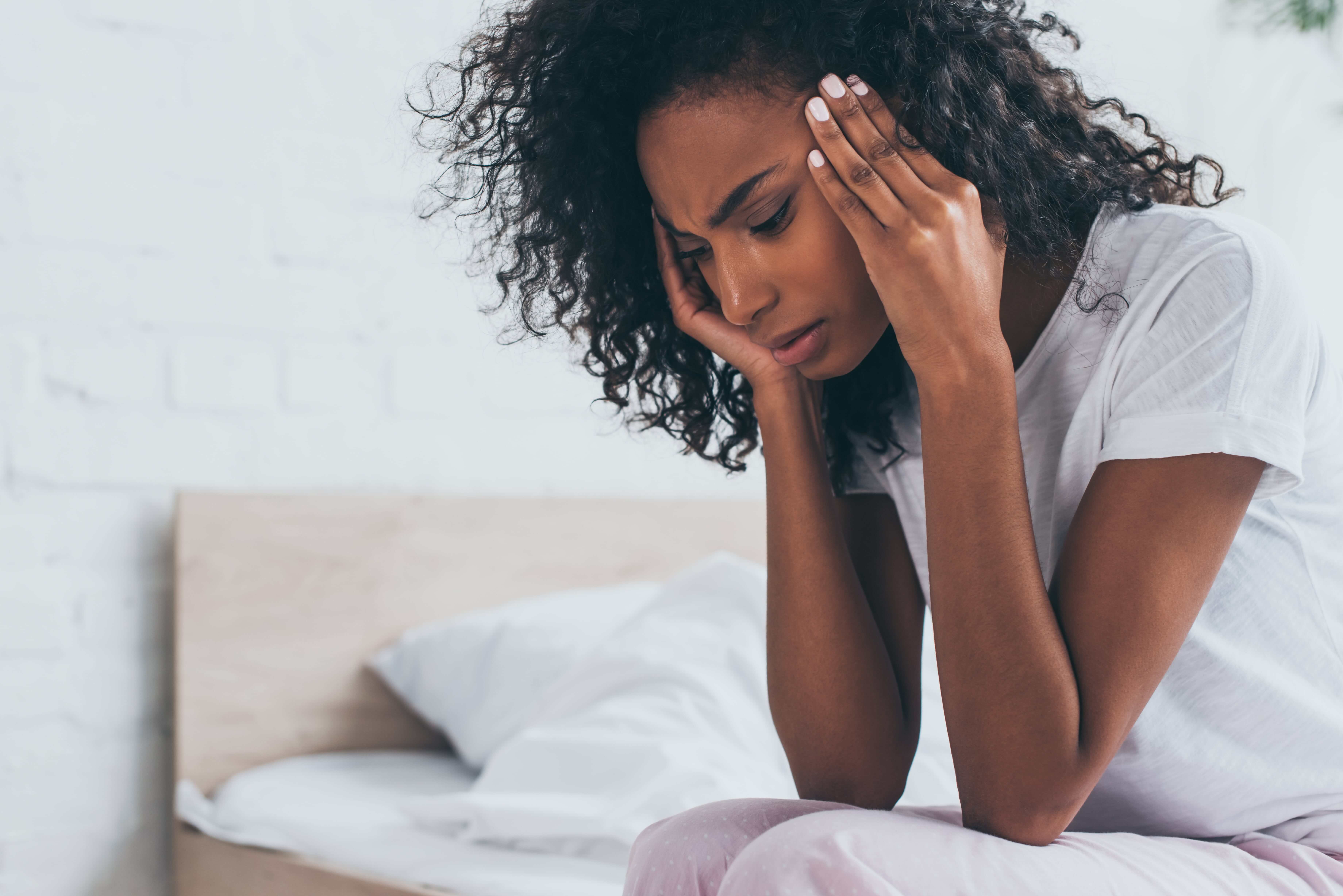 Woman with tension headache or migraine rubbing her head in pain.