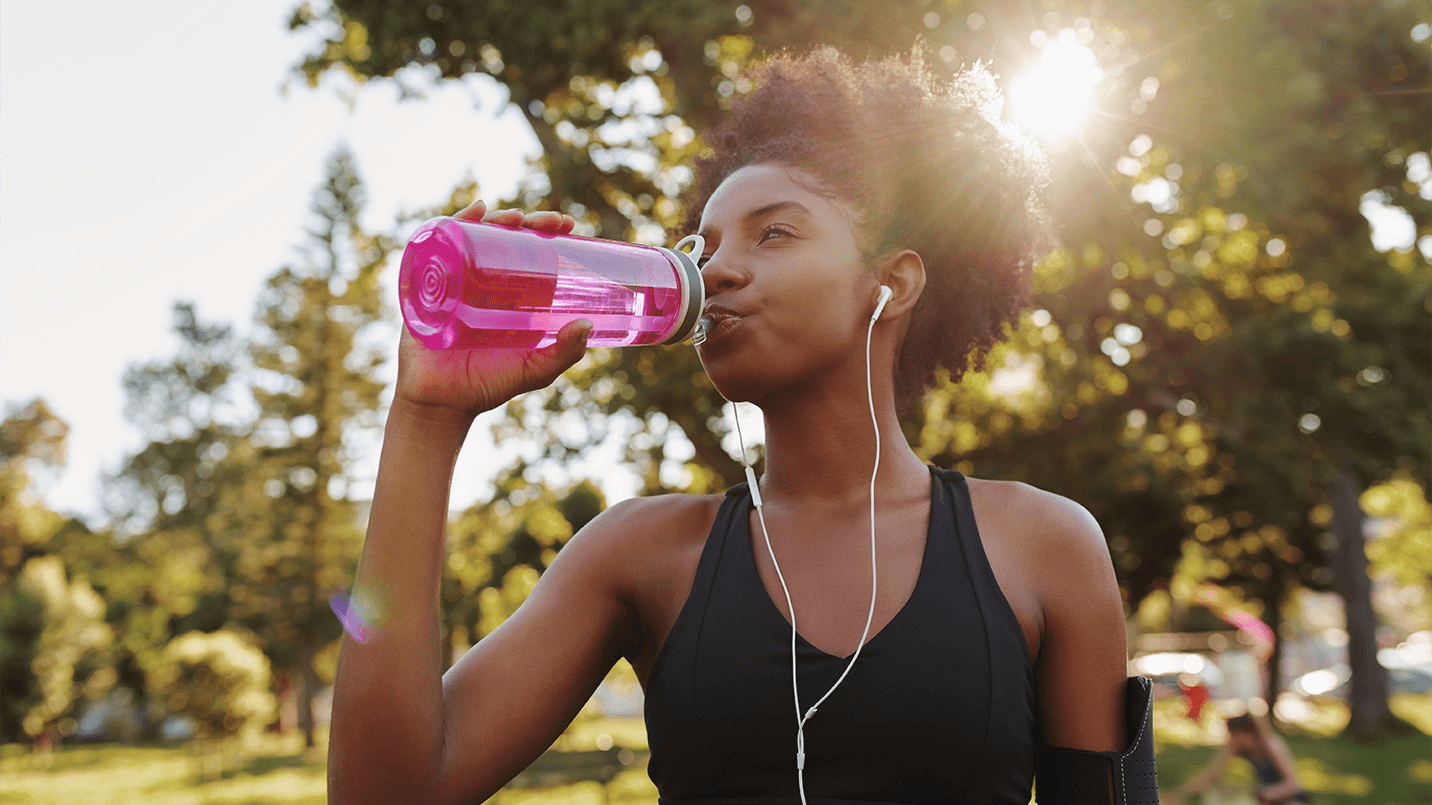 African American woman jogging outside and taking a water break