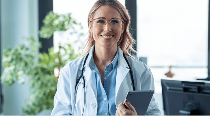 Female clinician holding a tablet with a smile on her face looking at the camera