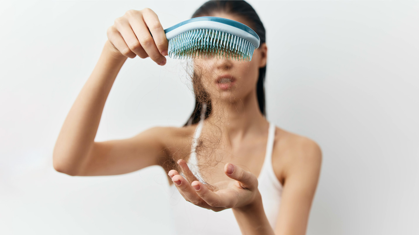 woman holding up a blue brush with hair hanging off of it