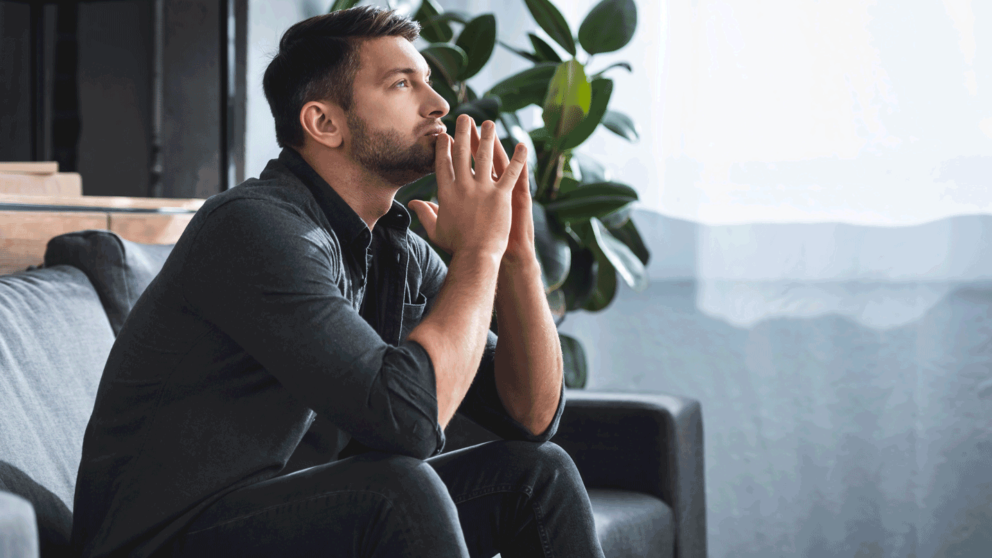 man sitting not a couch looking worried