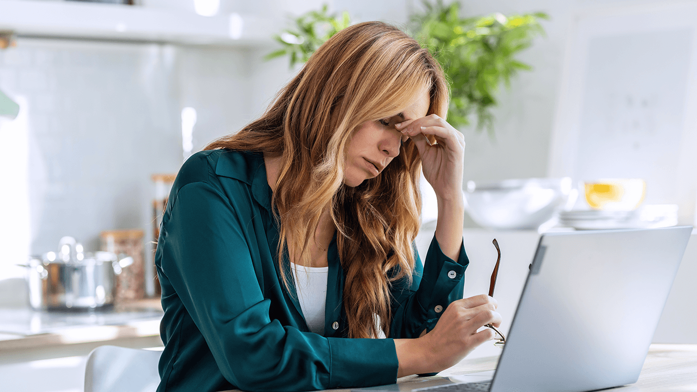 woman looking tired, sighing and pinching the bridge of her nose