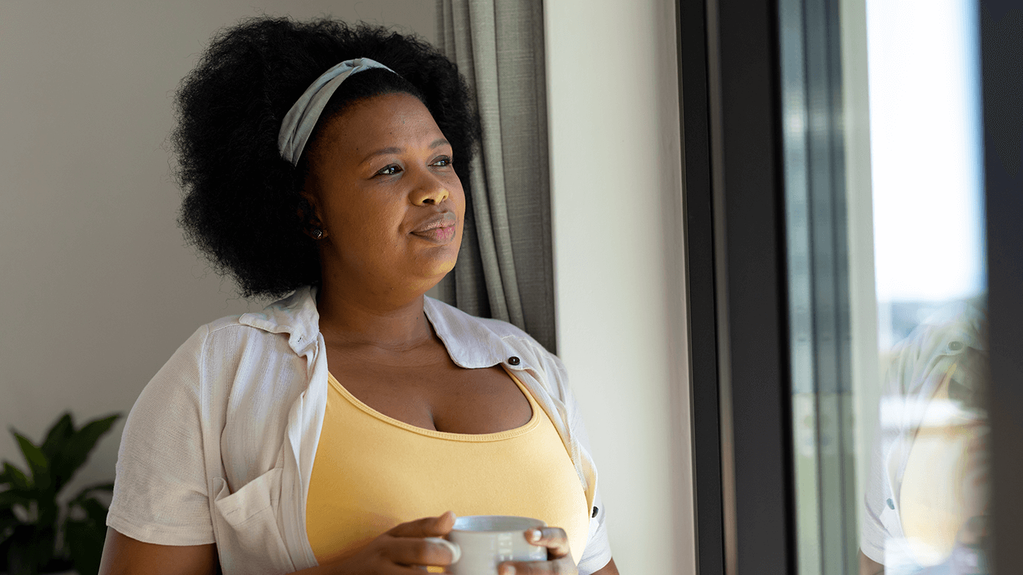 African American woman looking thoughtful while holding a cup of coffee