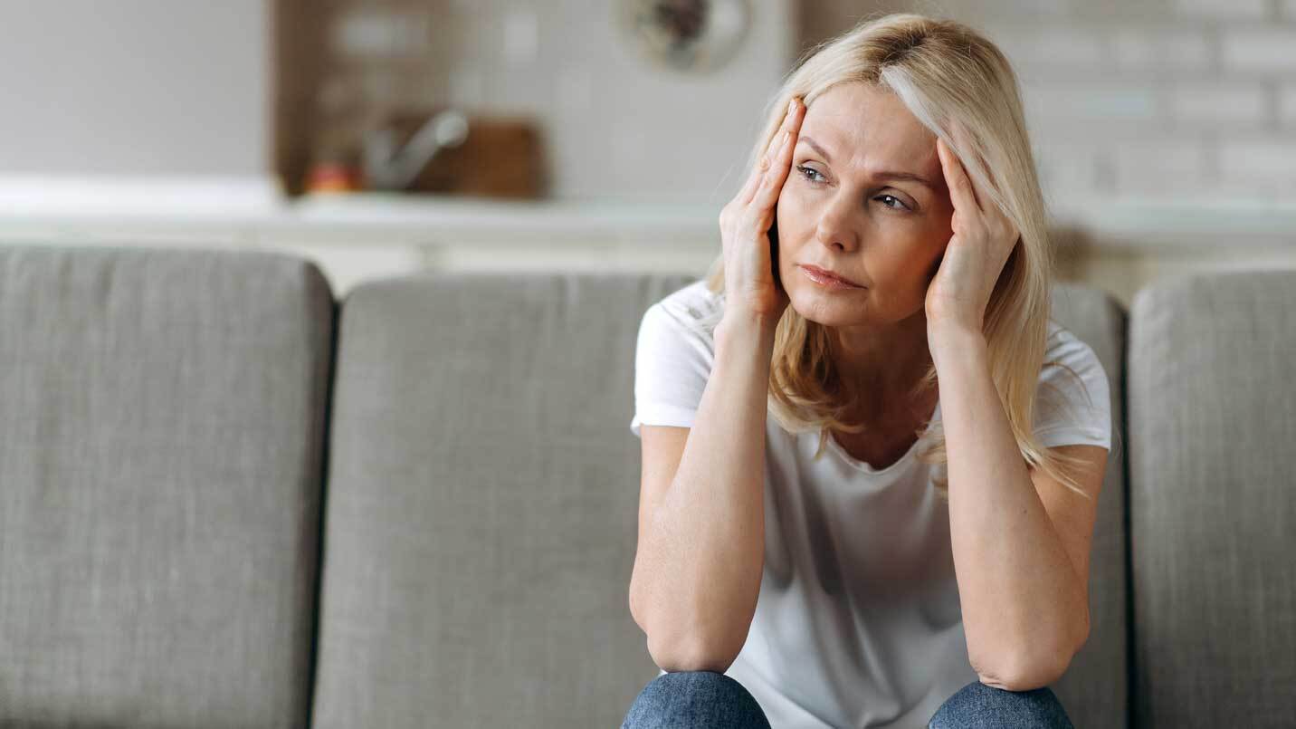 women holding her head between her hand and looking uncomfortable and tired