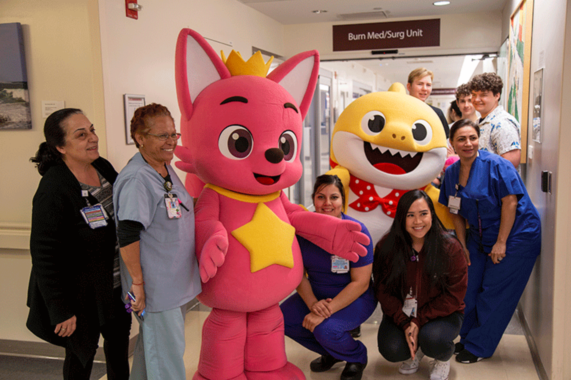Pinkfong and Baby Shark posing with some of the patients in the pediatric unit