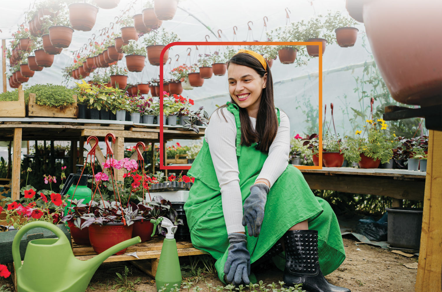 Woman with awesome rain boots tending to her garden inside a greenhouse. She loves being a Financial Center member!