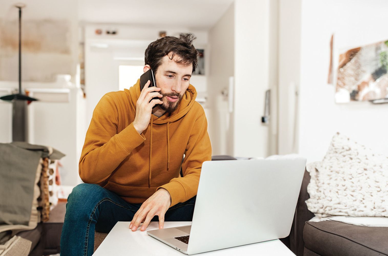 Man Sitting by his computer while speaking with Financial Center on the phone about Fraud