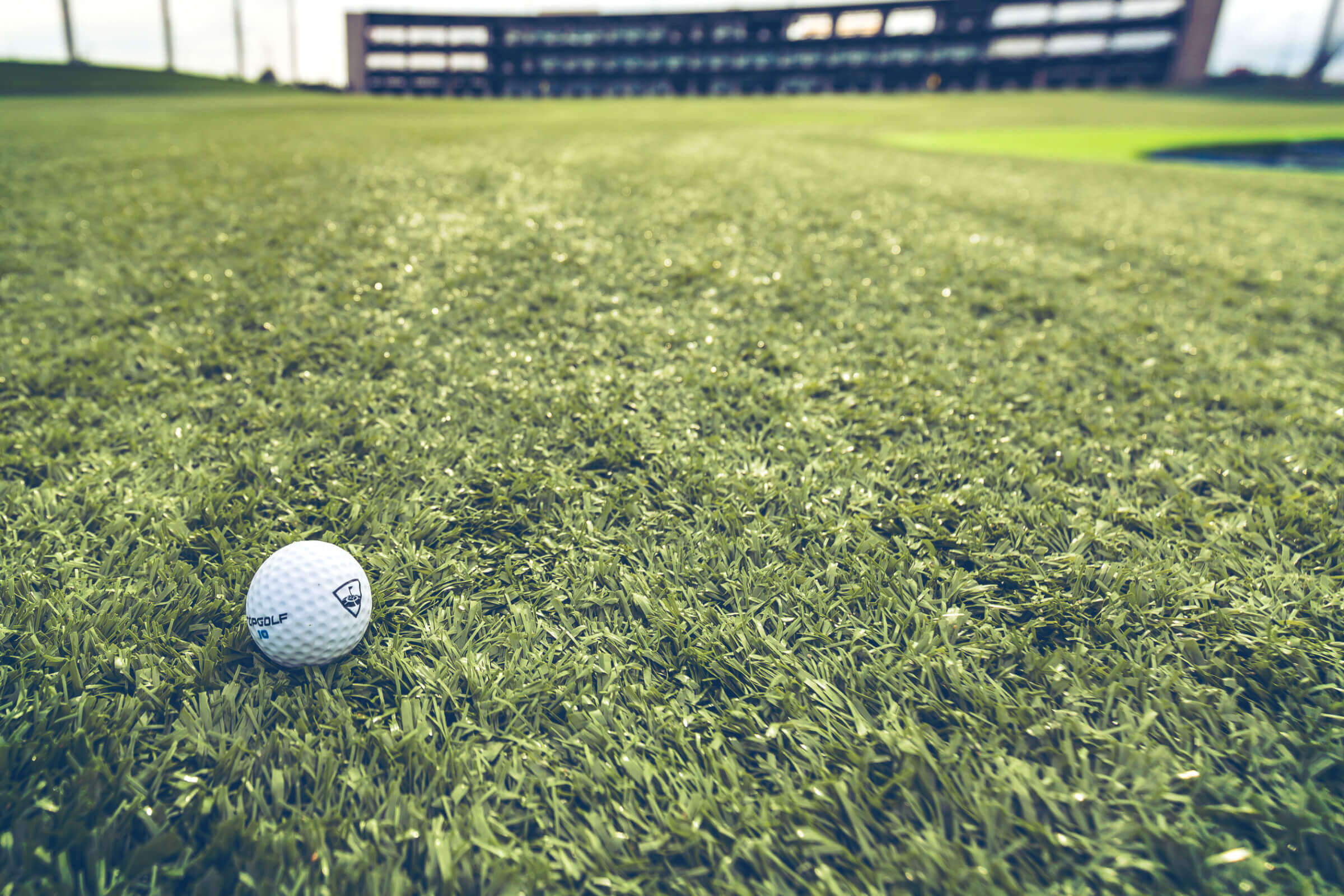 A golf ball sits on the grass in front of a building.
