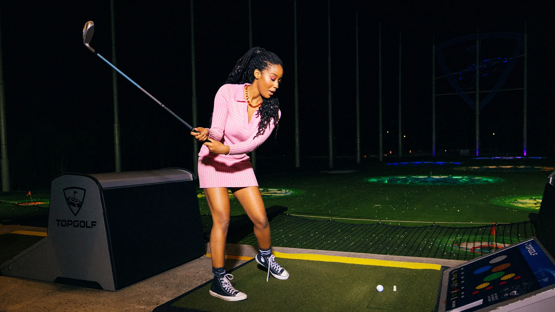 A woman in a pink dress enjoying a game of golf at the Gold Coast's popular entertainment complex, Topgolf.
