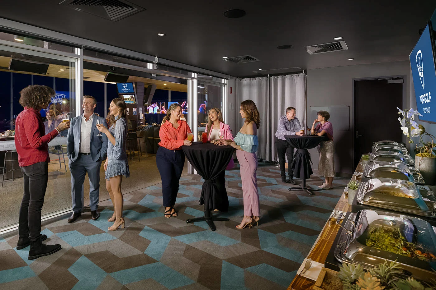 A group of people standing around a table at a Topgolf event space, capturing venue photos for their special occasion.