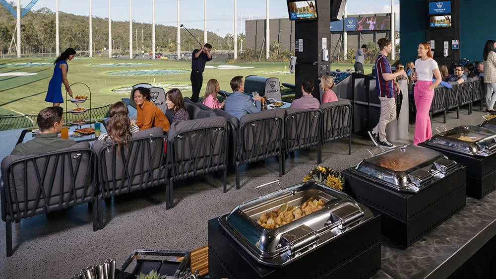A group of people playing golf and sharing delicious food at an event hosted at Topgolf Gold Coast.