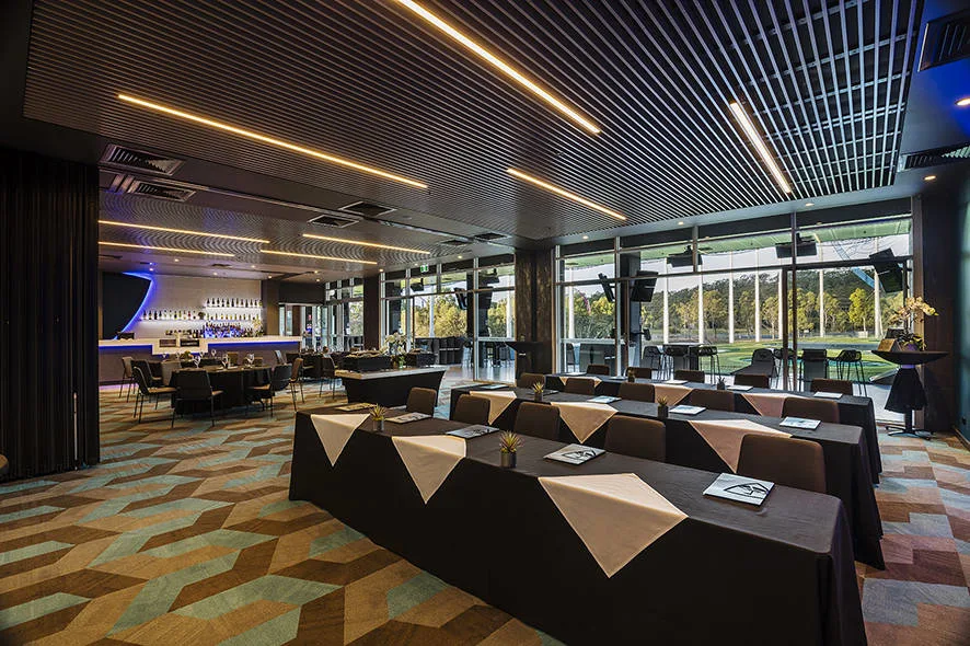 A spacious conference room at Topgolf Gold Coast with tables and chairs, ideal for hosting events, conferences or meetings.