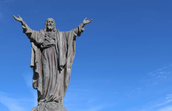 Neuvaine au Sacré Cœur de Jésus jour 6 - Statue du Christ levant les deux bras sur fond de ciel bleu.