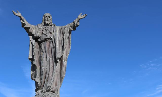 Neuvaine au Sacré Cœur de Jésus jour 6 - Statue du Christ levant les deux bras sur fond de ciel bleu.