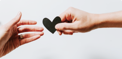 A love heart being passed from one person's hand to another's.