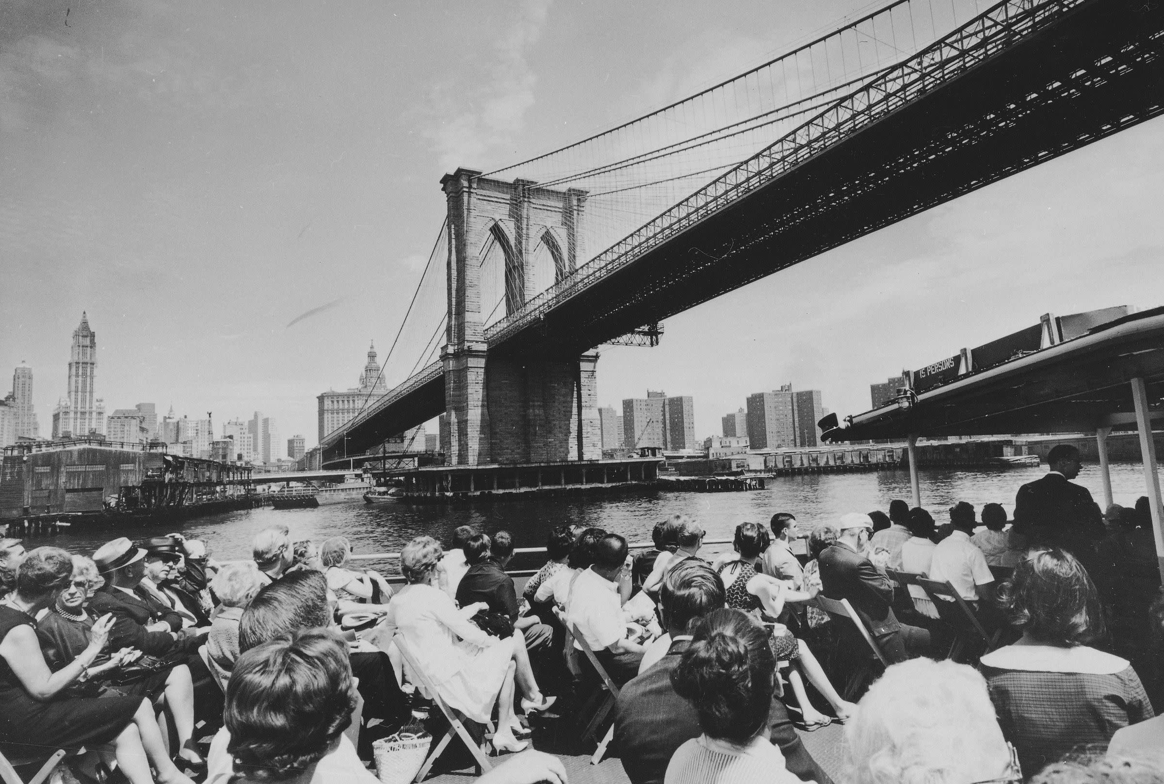 The Brooklyn Bridge looming over a sightseeing boat, July 3, 1964