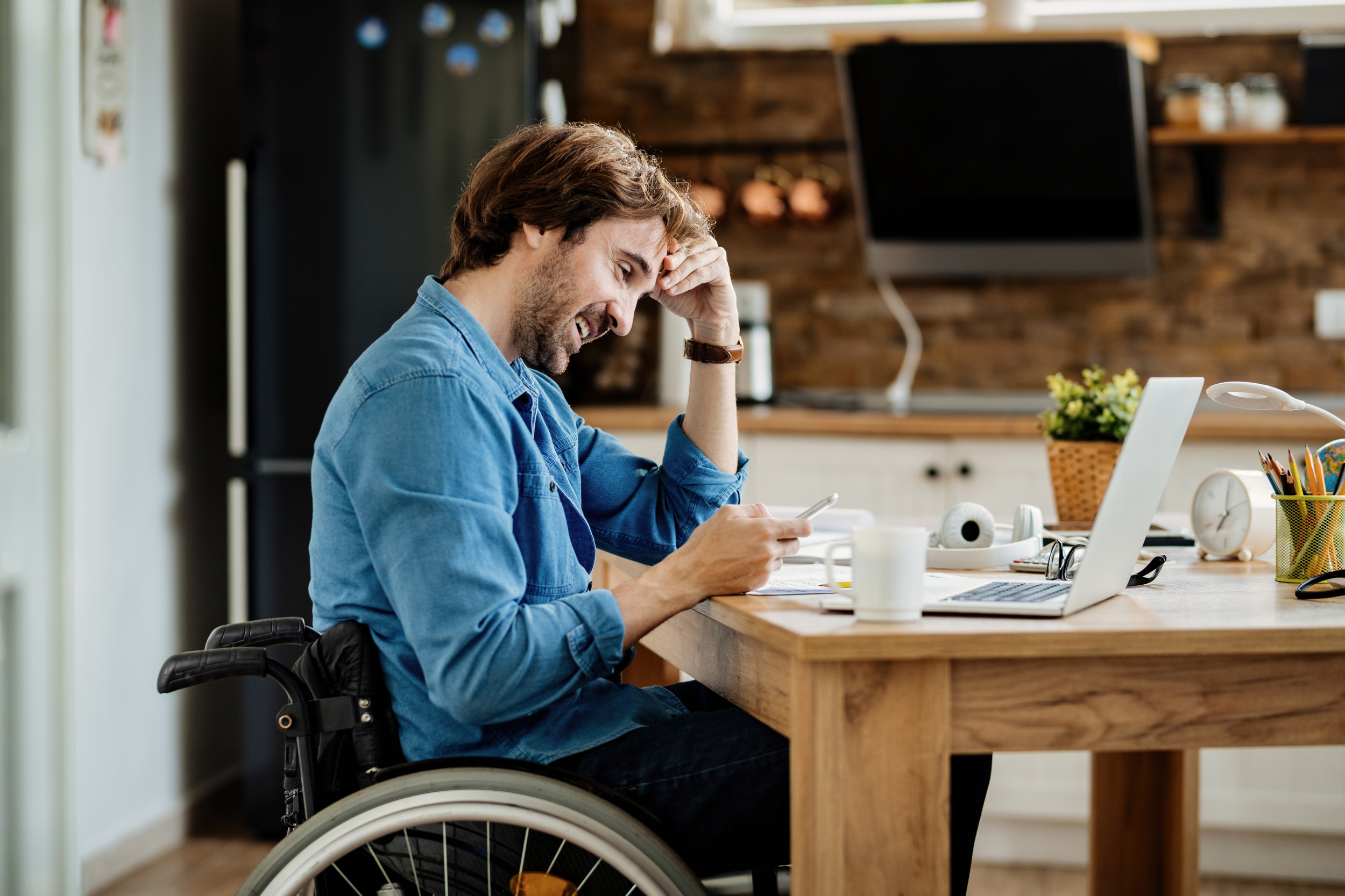 young-happy-businessman-wheelchair-working-home-text-messaging-mobile-phone