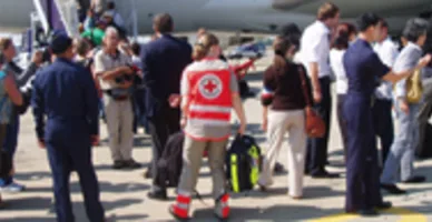 Les volontaires de la Croix-Rouge et les touristes rapatriés montent dans l’avion à l’aéroport de Bangkok.