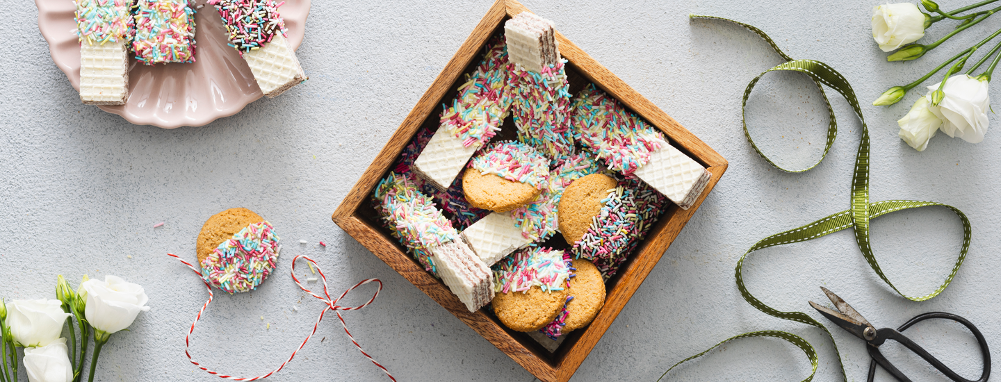 Suklaassa ja strösselissä dipattuja vohvelikeksejä sekä kaurakeksejä. Keksit on aseteltu pieneen puiseen laatikkoon. Laatikon vieressä on lahjanauhaa. K-Ruoka jouluresepti.