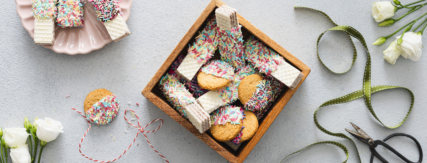 Suklaassa ja strösselissä dipattuja vohvelikeksejä sekä kaurakeksejä. Keksit on aseteltu pieneen puiseen laatikkoon. Laatikon vieressä on lahjanauhaa. K-Ruoka jouluresepti.