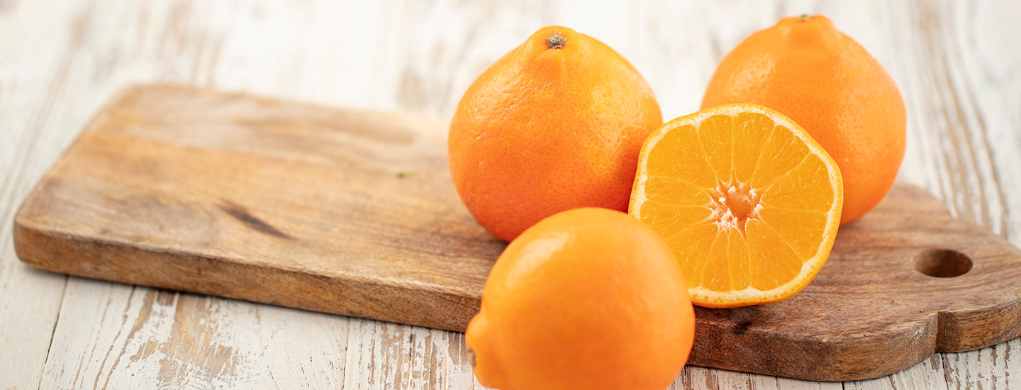Tuoreita kuorellisia mandariineja puisen leikkuulaudan päällä. Yksi mandariini on leikattu puolikkaaksi. K-Ruoka raaka-aine.