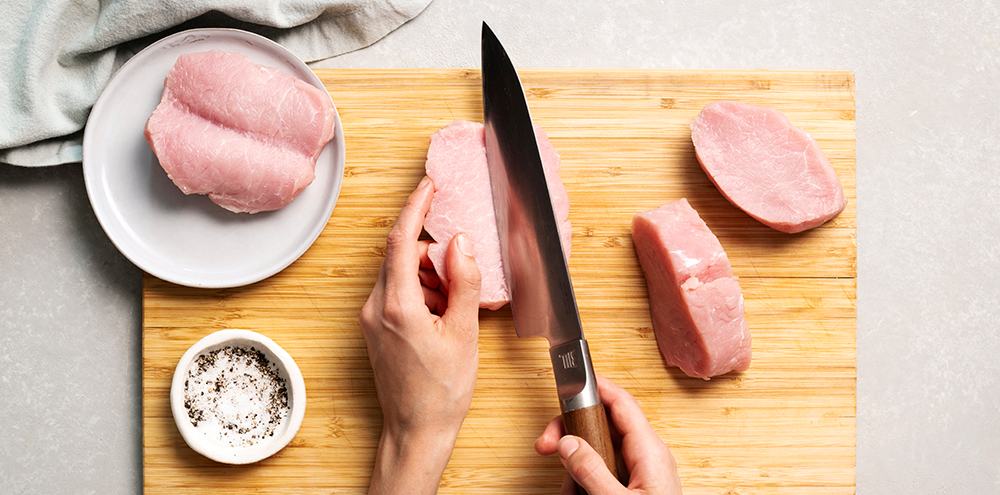 Porsaan ulkofileitä leikkuulaudalla. Yhtä fileetä ollaan leikkamassa puolittain.