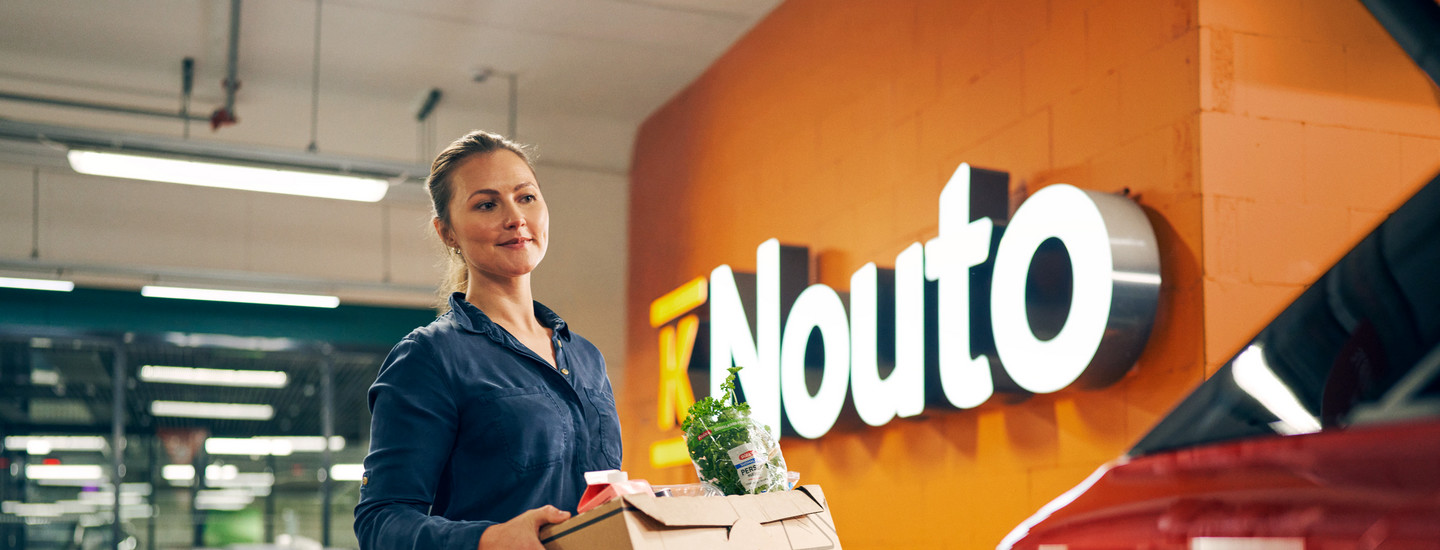Nainen kantaa ruokaostoksiaan pahvilaatikossa