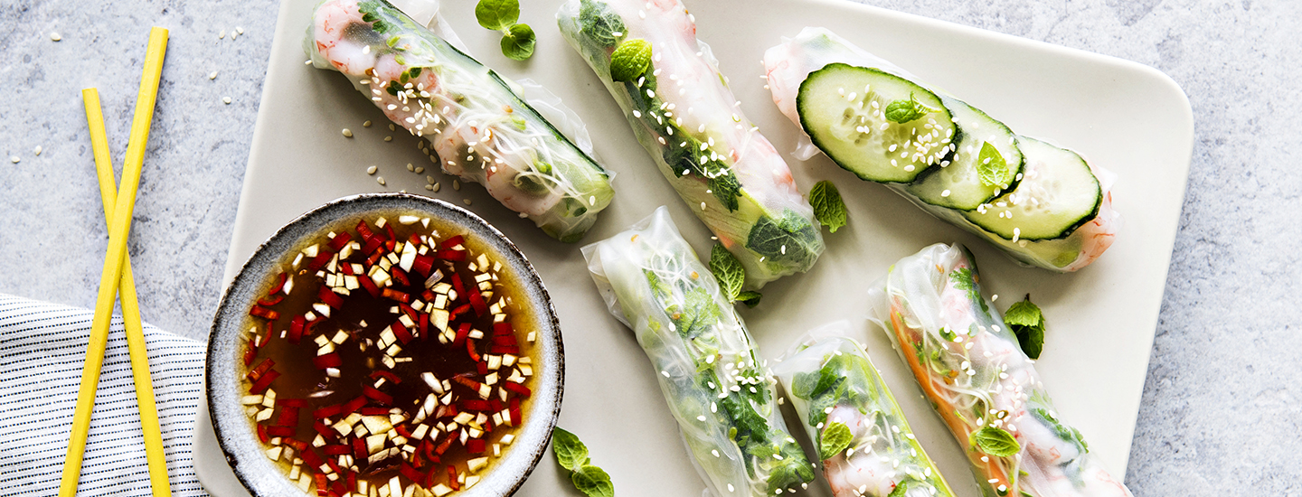 Vietnamilaisia kesärullia valkoisella lautasella, vieressä pieni kuppi, jossa on dippikastiketta kesärullille.