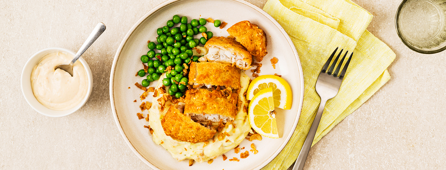 Rapeita kalapaloja perunamuusin ja herneiden kanssa lautasella. Annoksen vieressä on sitruunaviipaleita. K-Ruoka arkiruokaresepti.