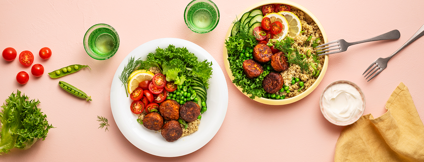 Bowl-annoksia kahdella eri lautasella. Annokset on koottu kvinoasta, salaatista, herneistä, tomaateista ja kalapihveistä. K-Ruoka arkiruokaresepti.