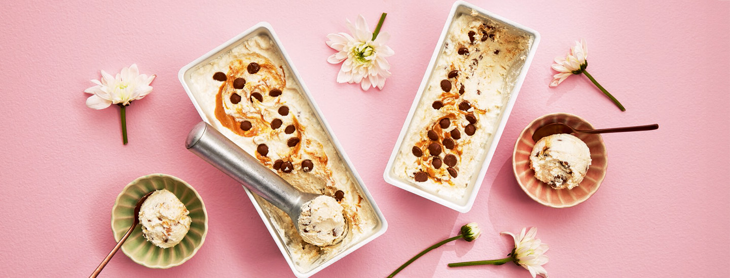 Raejuustojäätelöt astioissa vaaleampunaisella alustalla, jossa on kukkia.