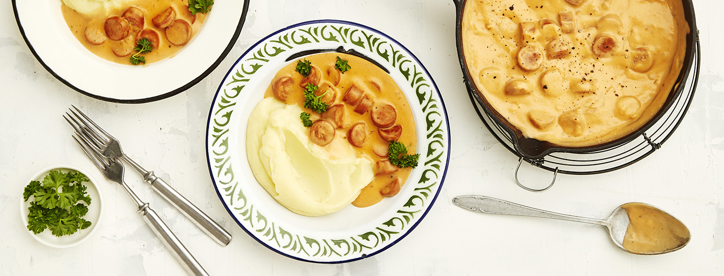 Ruskeaa nakkikastiketta vegaanisista nakeista ja perunamuusia lautasella. Nakkikastikkeen päälle on ripoteltu tuoretta persiljaa. K-Ruoka arkiruokaresepti.