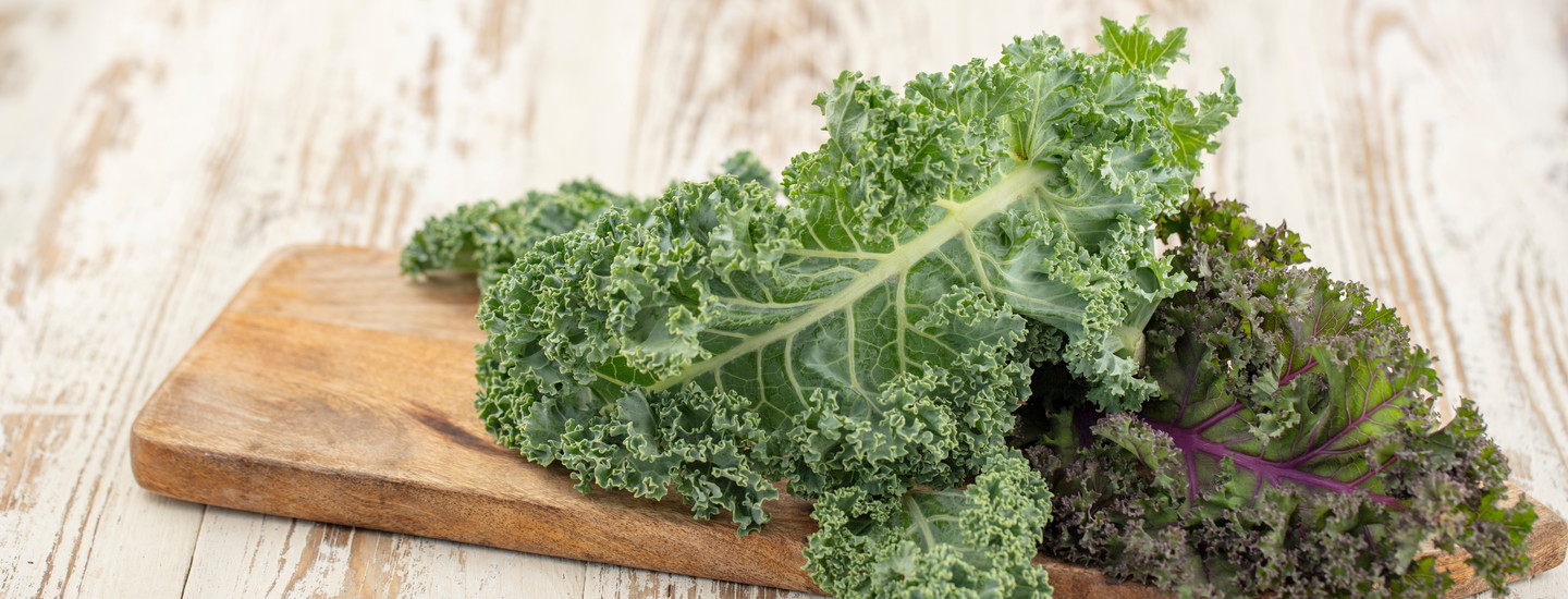 Tuoretta lehtikaalia puisen leikkuulaudan päällä.