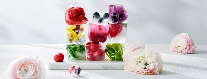 Päällekkäin olevia jääpaloja, joissa on sisällä marjoja, syötäviä kukkia ja yrttejä.