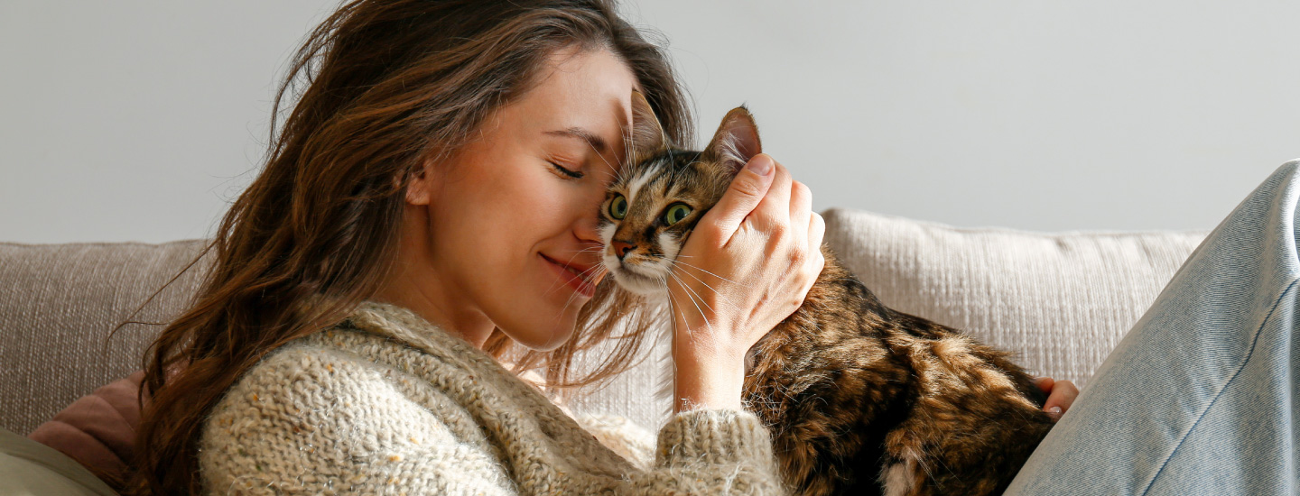 Nainen ja kissa halivat sohvalla