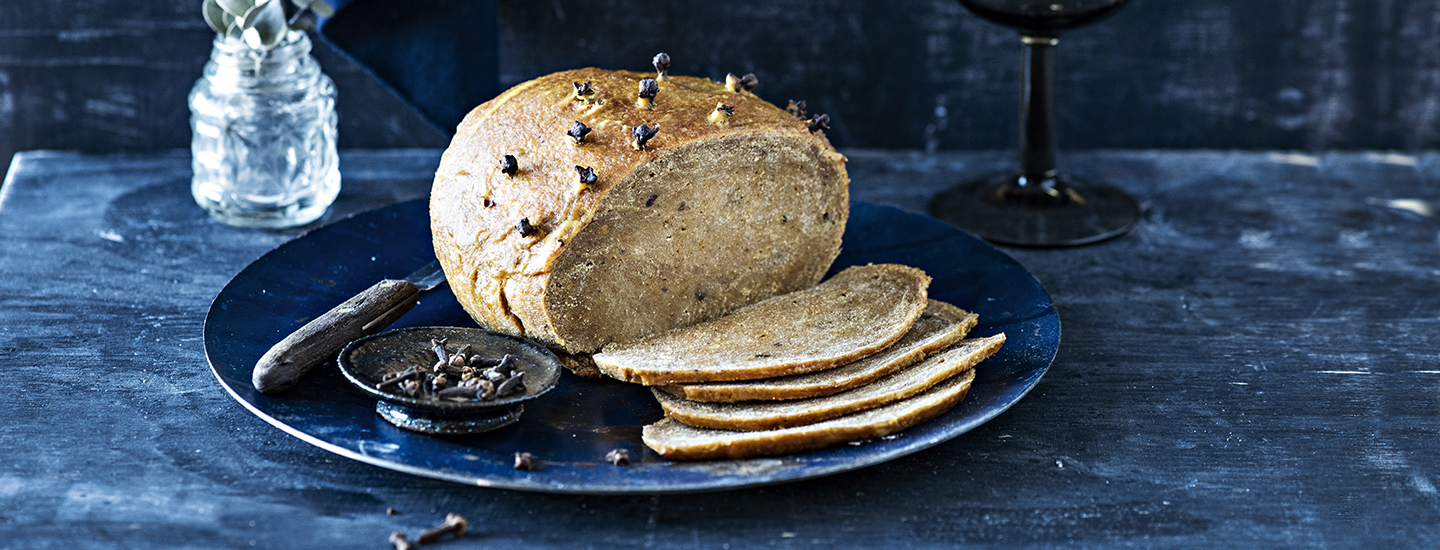 Seitankinkku tummansinisellä lautasella. Seitankinkusta on leikattu viipaleita. K-Ruoka vegaaninen jouluresepti.