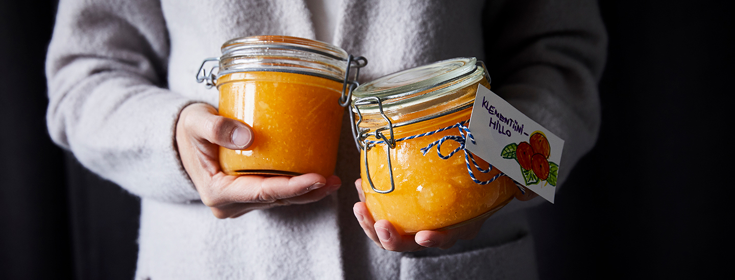 Ihminen pitelemässä kahta lasipurkkia, joissa on klementiinihilloa. K-Ruoa hilloresepti.