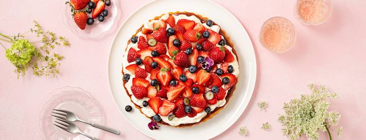 Tuoreita marjoja ja mascarpone-vaniljavaahtoa makean piirakkapohjan päällä. Mascarpone-vaniljavaahtokerroksen alla on kerros mansikka-raparperihilloa. Kakku on koristeltu syötävillä orvokeilla. K-Ruoka jälkiruokaresepti.