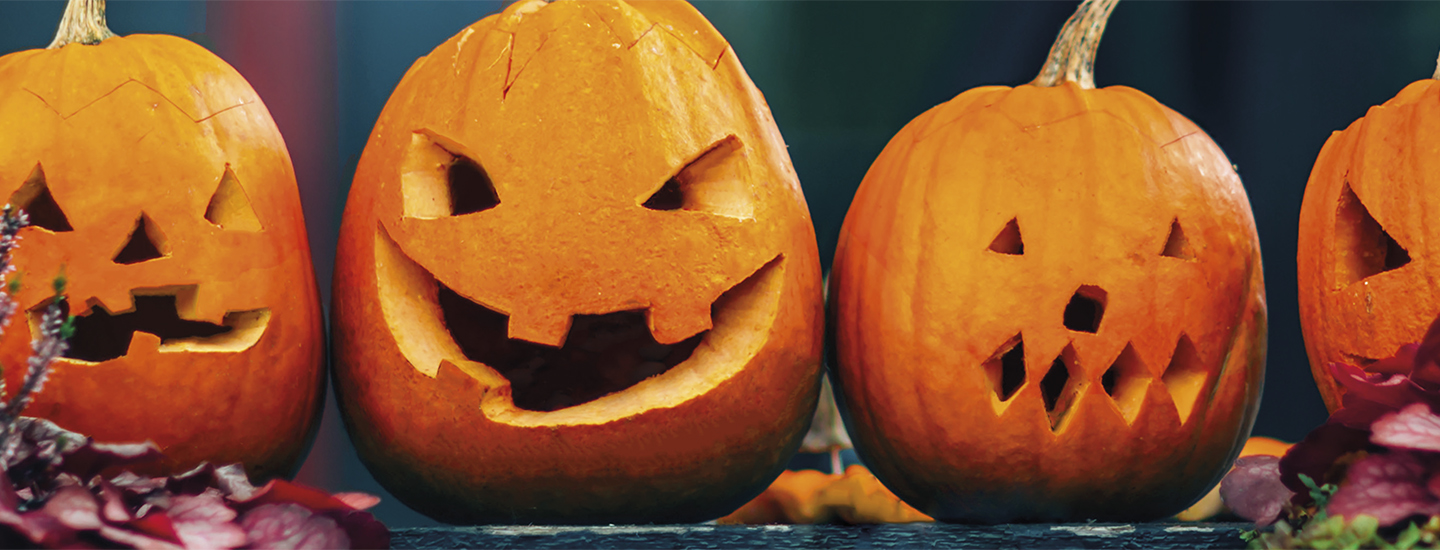 Kuvassa neljä kaiverrettua kurpitsaa. 