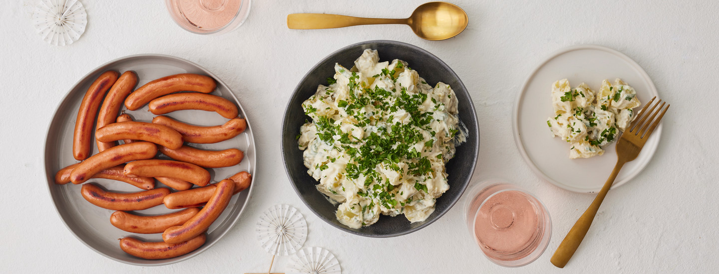 Itsetehtyä perunasalaattia ja nakkeja lautasilla. K-Ruoka salaattiresepti.