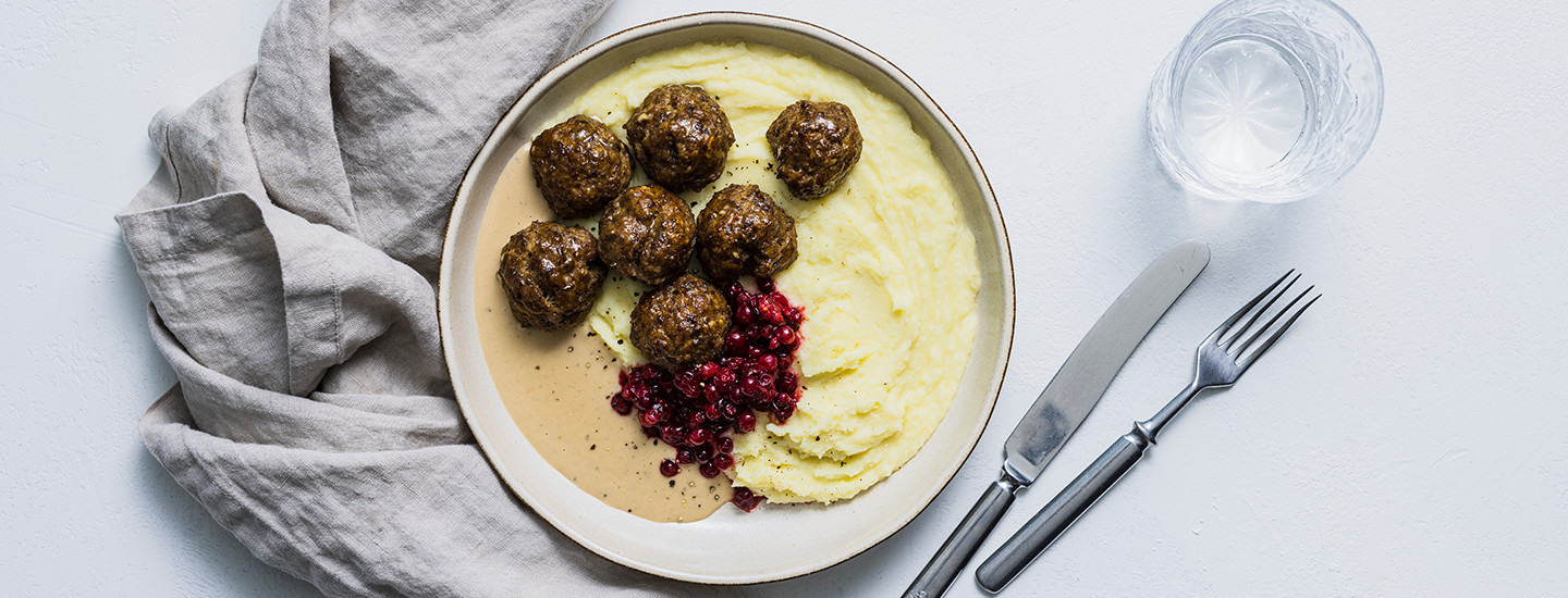 Lihapullia ja perunamuusia vaalealla lautasella. Lautasella on myös ruskeaa kastiketta ja puolukkasurvosta. K-Ruoka arkiruokaresepti.