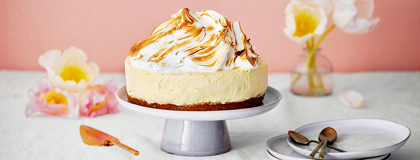 Sitruuna-marenkijuustokakku vaalealla kakkulautasella. Sitruunaisen juustokakkutäytteen päällä on valkoinen marenkikeko, jonka pintaa on hieman paahdettu rusehtavaksi. K-Ruoka juustokakkuresepti.