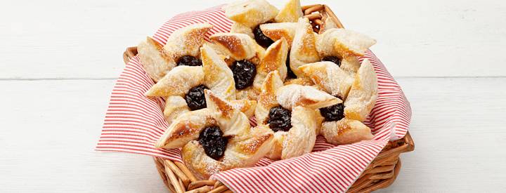 Joulutorttuja pienessä korissa, jossa on puna-valkoraidallinen lautasliina.