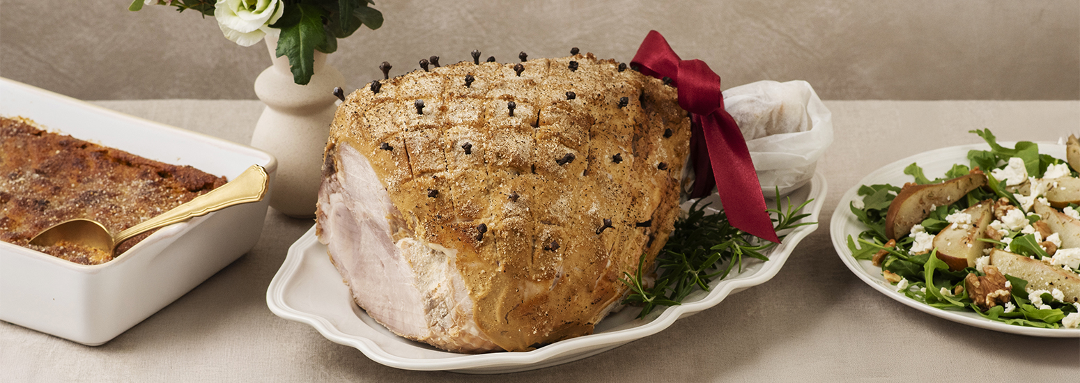 Kokonainen kuorrutettu joulukinkku valkoisella tarjottimella. Kinkku on kuorrutettu sinappihunnulla. K-Ruoka jouluresepti.