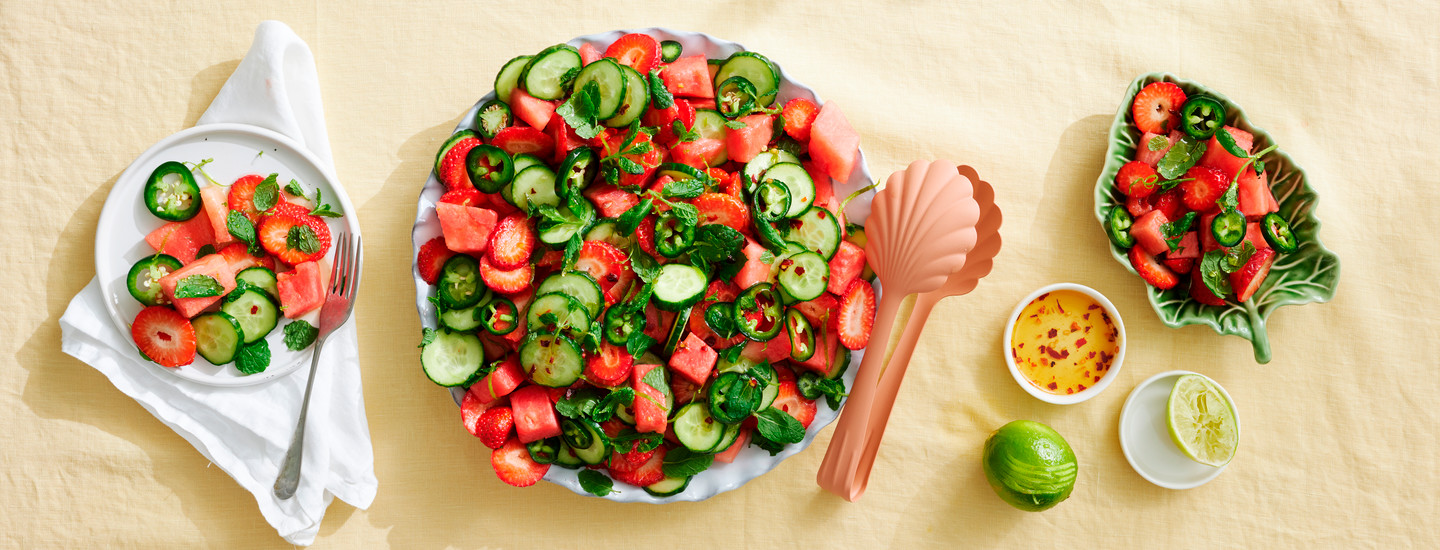 Vesimeloni-kurkkusalaattia valkoisessa tarjoilukulhossa. Salaatin seassa on myös tuoreen jalapenon siivuja sekä tuoreita yrttejä. K-Ruoka salaattiresepti.