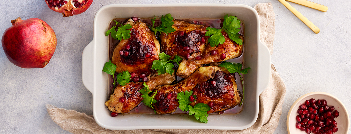 Paahdettuja kanankoipia ja granaatinomenansiemeniä uunivuoassa. Kanankoipien päälle on ripoteltu tuoretta lehtipersiljaa. K-Ruoka kanaresepti.