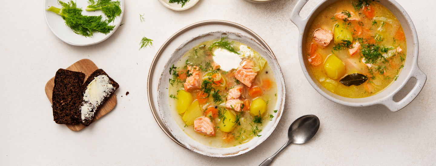 Fenkoli-lohikeittoa keittolautasella ja vaaleassa padassa. Keittolautaselle on lisätty nokare ranskankermaa. K-Ruoka keittoresepti.