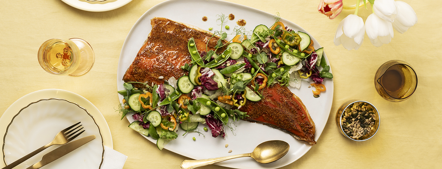 Savulohifilee valkoisella tarjoilulautasella. Savulohen päälle on aseteltu vihersalaattia, jossa on kurkkua, herneitä ja paprikaviipaleita. K-Ruoka resepti.