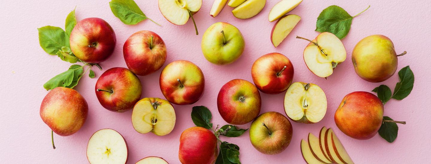 Omenoita vaaleanpunaisella taustalla.